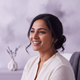A smiling South Asian woman in her mid-30s, looking content and relieved in a close-up portrait.